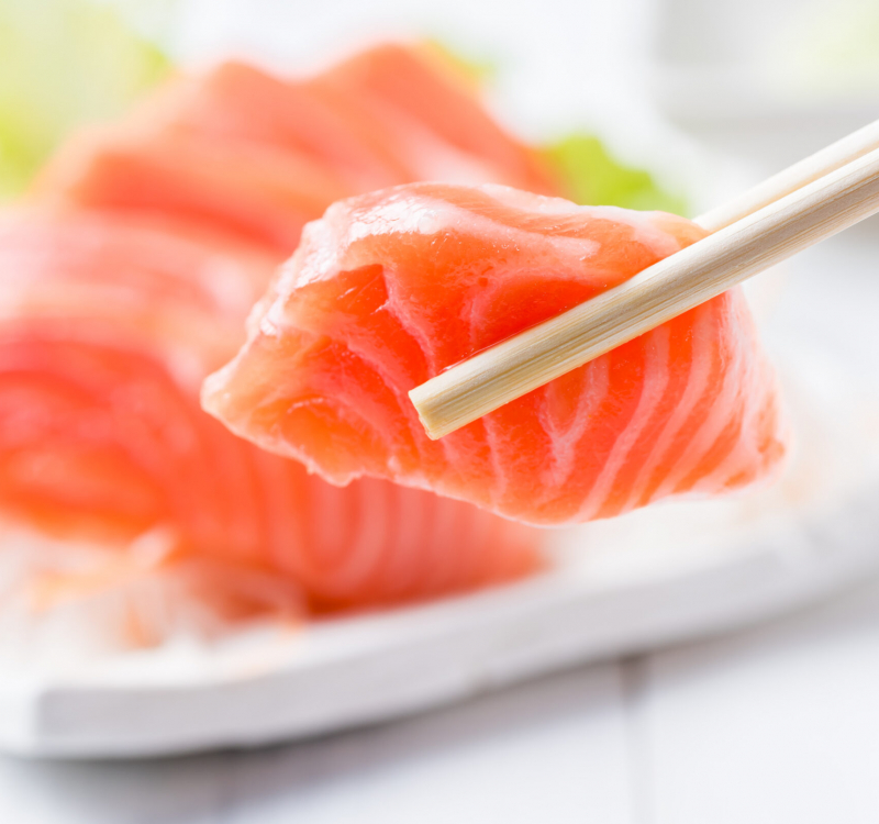 closed up of salmon sashimi set with chopsticks holding a piece of sliced salmon, healthy food and diet